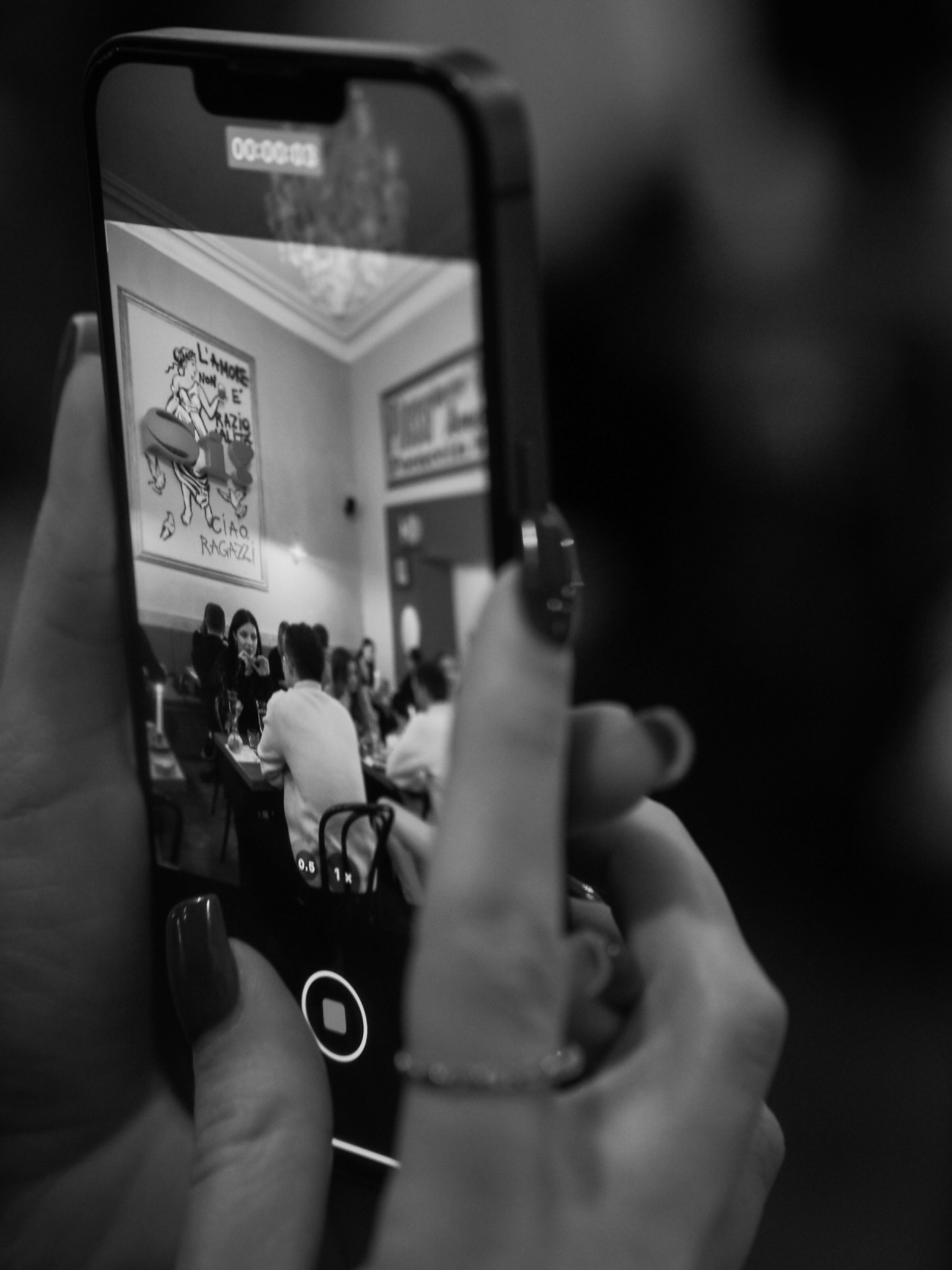Black-and-white documentary photograph of a guest filming an event