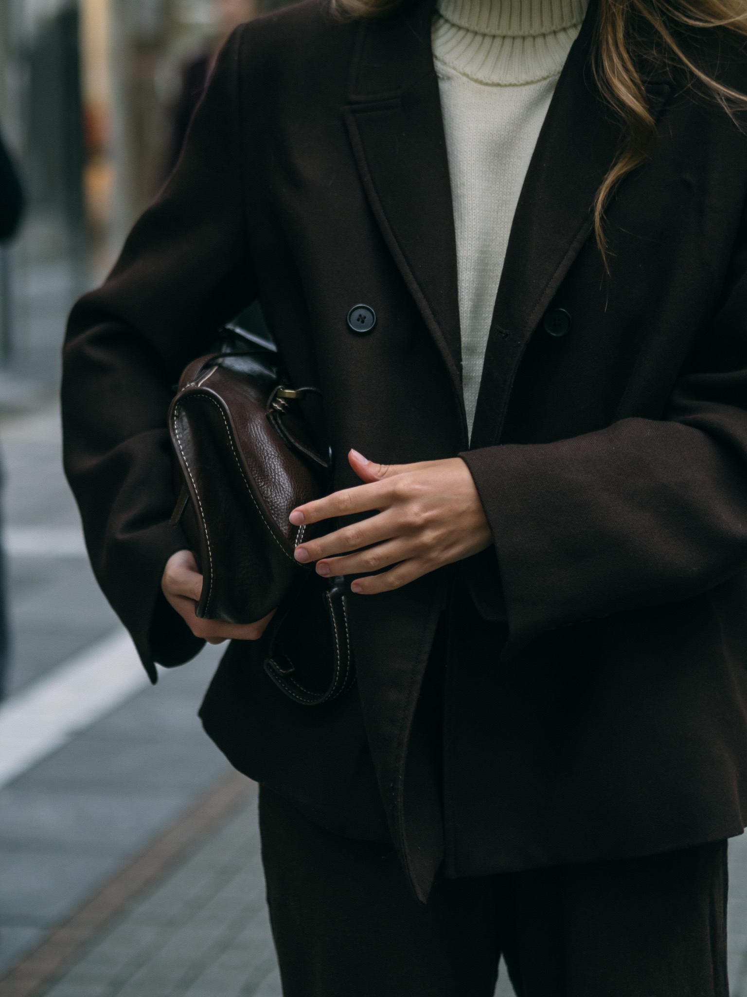 Fashion detail of a dark suit and leather bag